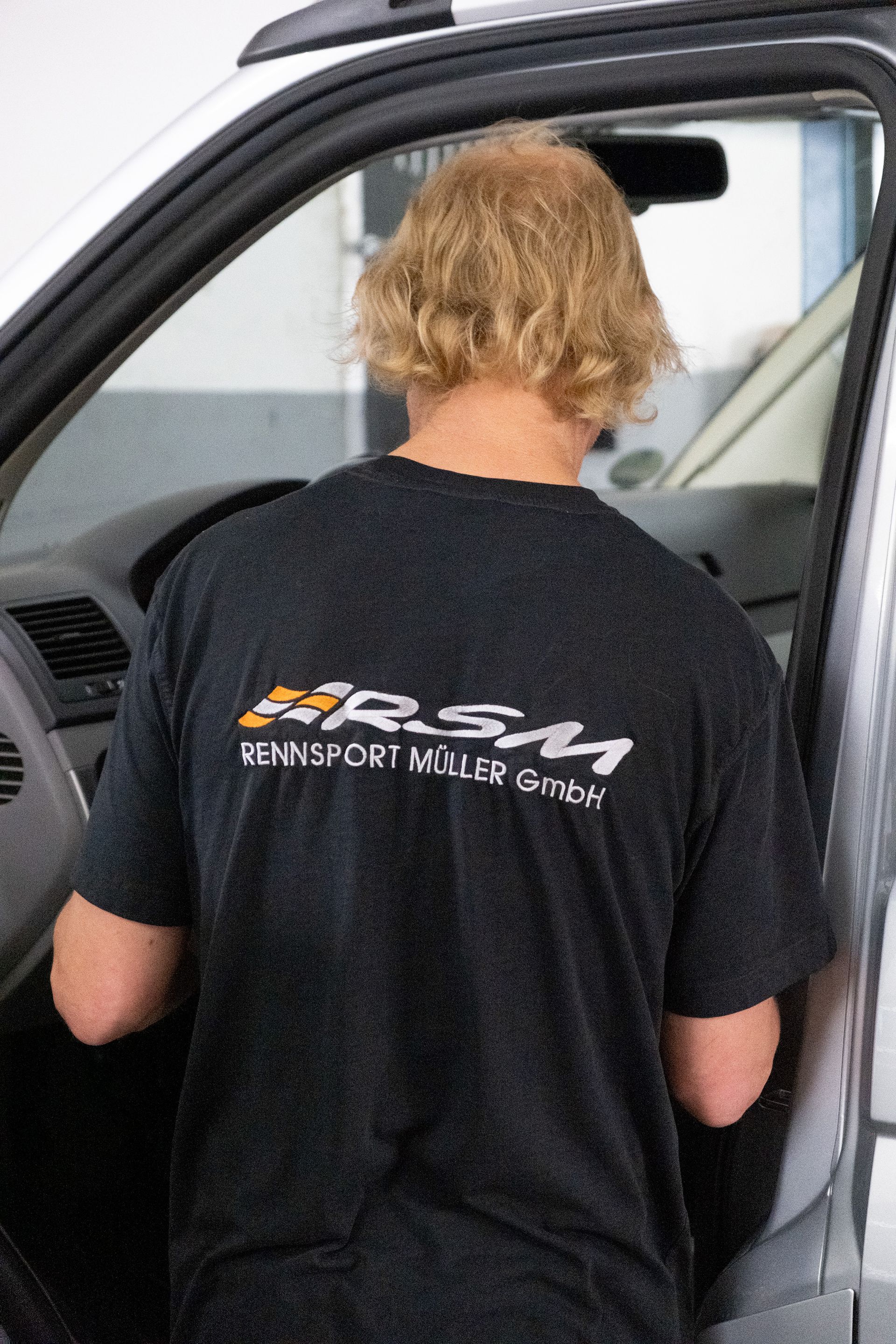 Eine Person bedient eine Industriemaschine. In einem Metallkasten greift sie mit den Händen in einen Arbeitsbereich.