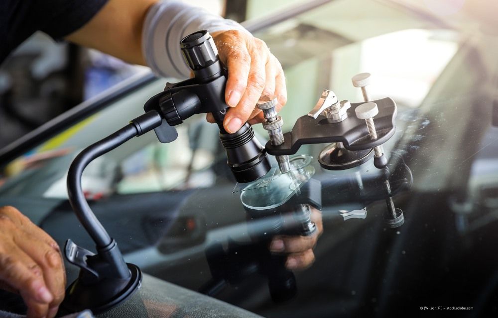 Eine Person benutzt ein Reparaturwerkzeug, um einen Riss in einer Autowindschutzscheibe auszubessern.