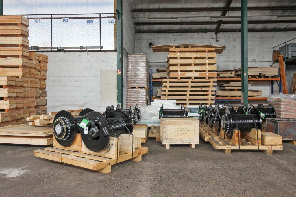 Intérieur d'un entrepôt industriel avec des pièces de machines sur des palettes en bois, des piles de bois.