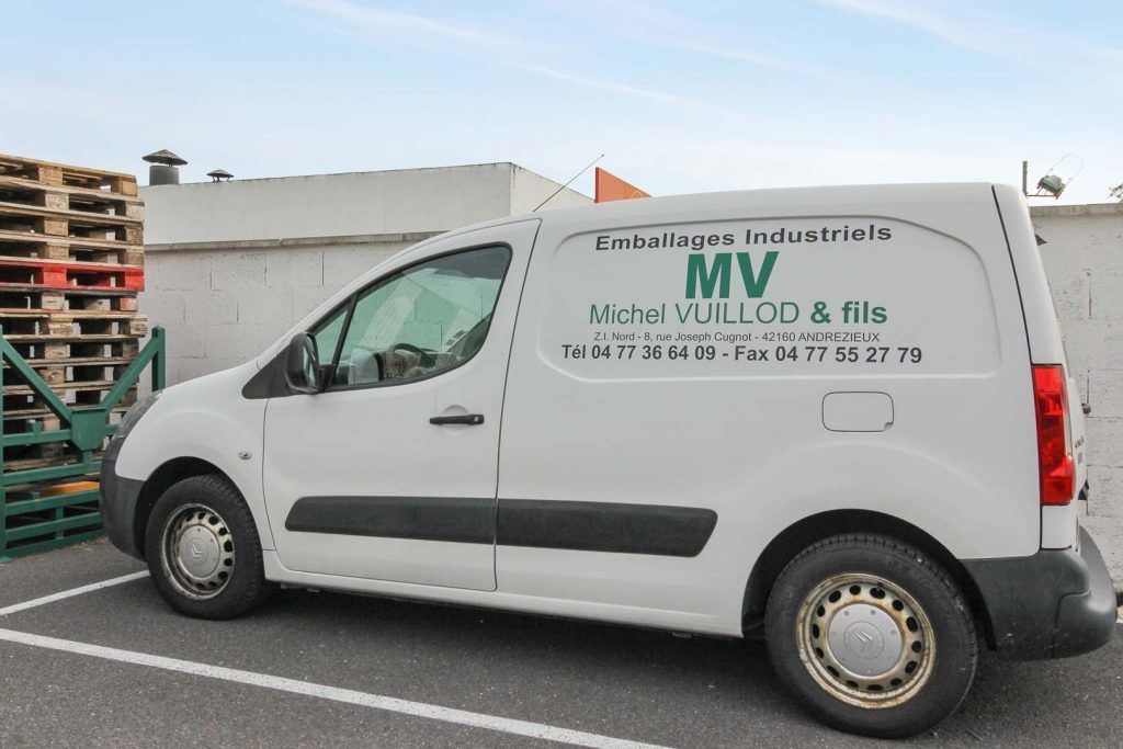 White delivery van parked next to pallets,