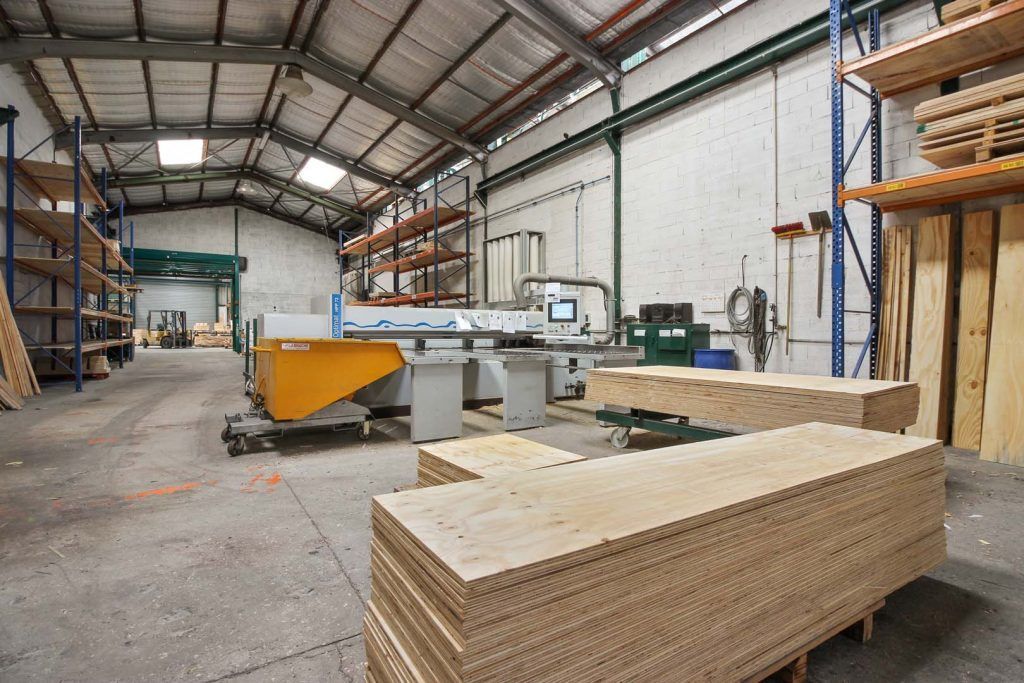 Intérieur d'un entrepôt avec des machines à bois et des piles de contreplaqué.