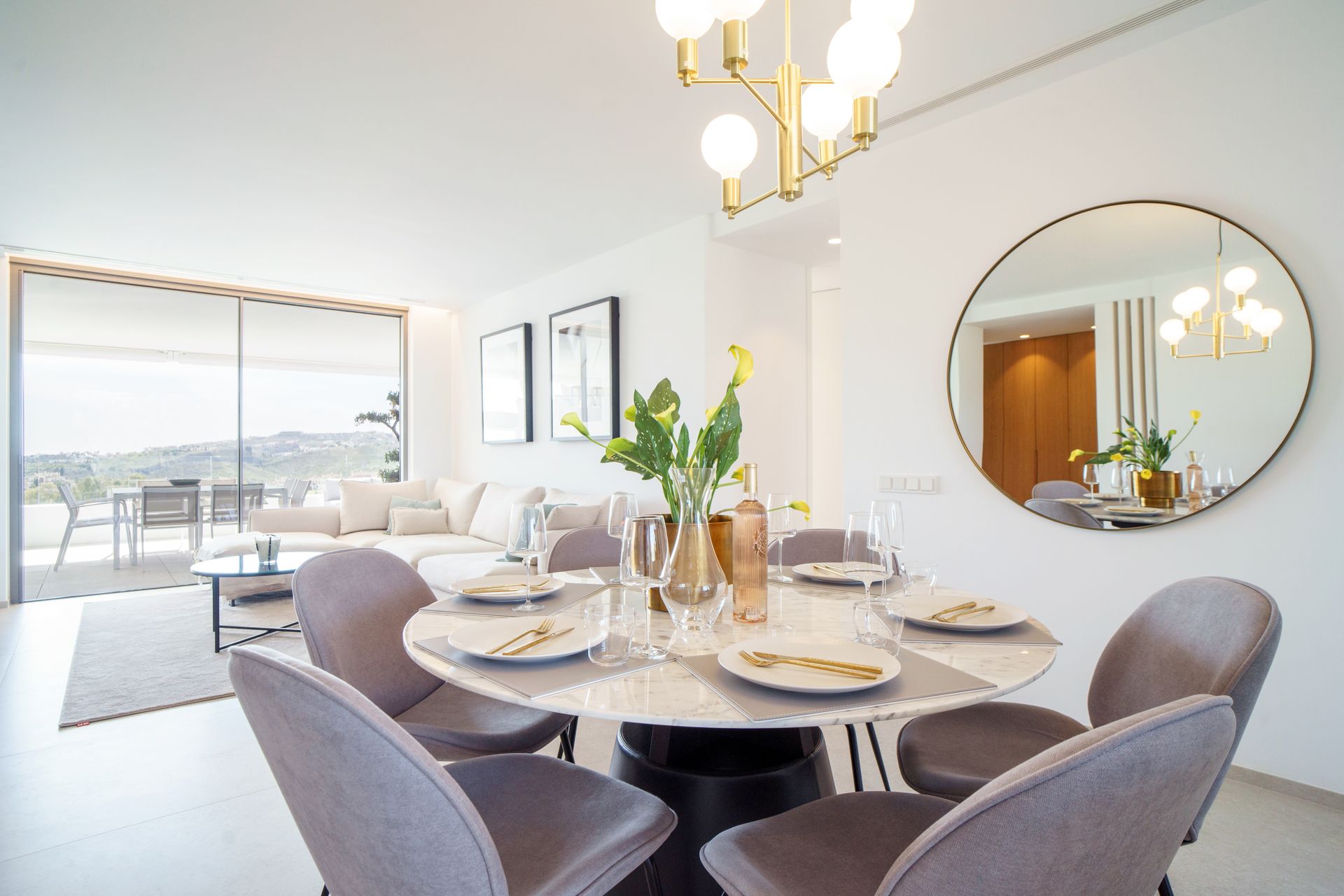 A dining room with a table and chairs and a large mirror.