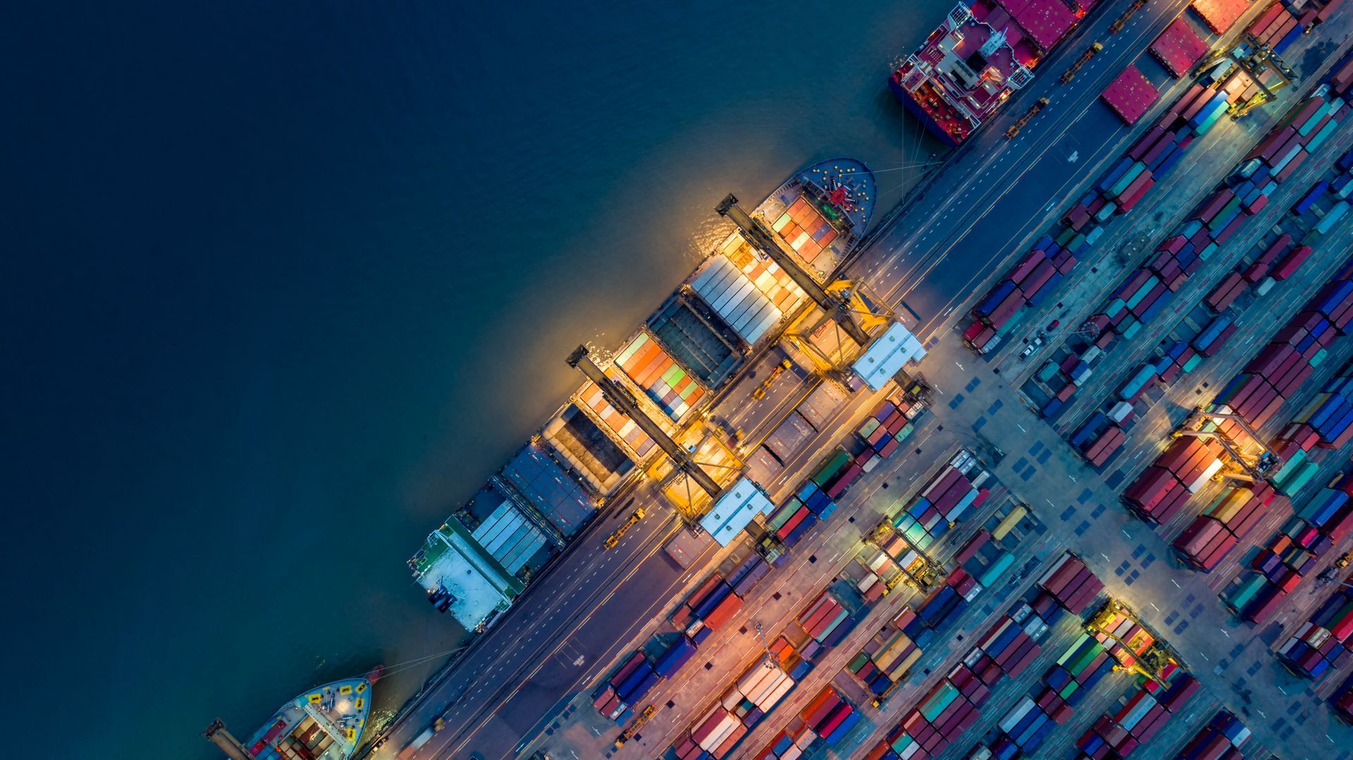 Ein Frachtschiff, ein Lastwagen und ein Flugzeug in einem Hafen bei Sonnenuntergang – Symbole für globalen Handel und Logistik.