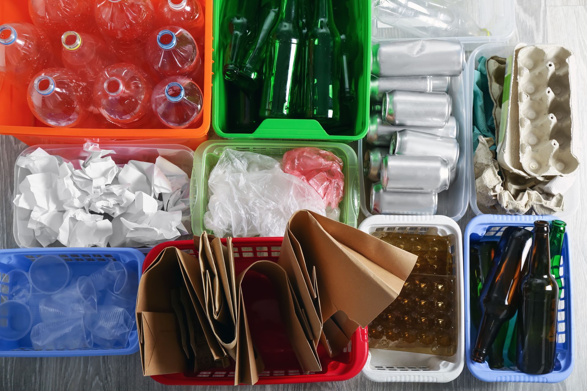 Zwei Personen mit Schutzhelmen und Warnwesten stehen vor roten Schiffscontainern; eine von ihnen zeigt mit dem Finger und hält dabei eine Mappe in der Hand.