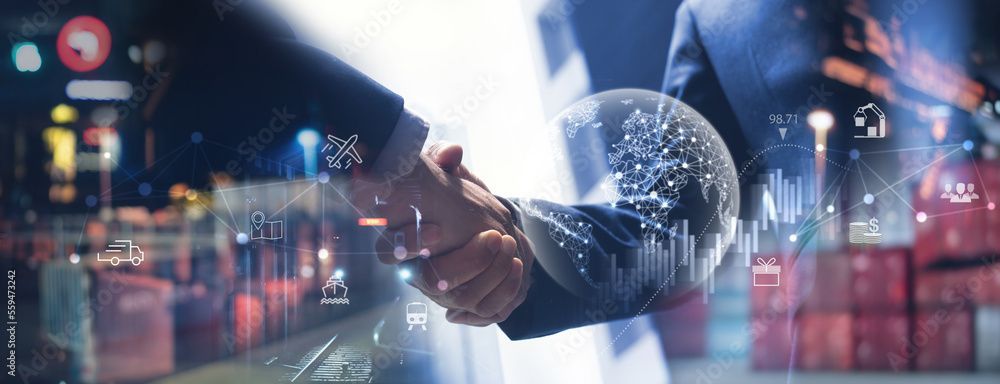 Zwei Personen schütteln sich vor einem verschwommenen Industriehintergrund mit digitalen Datenüberlagerungen und einer leuchtenden Globusgrafik die Hände.