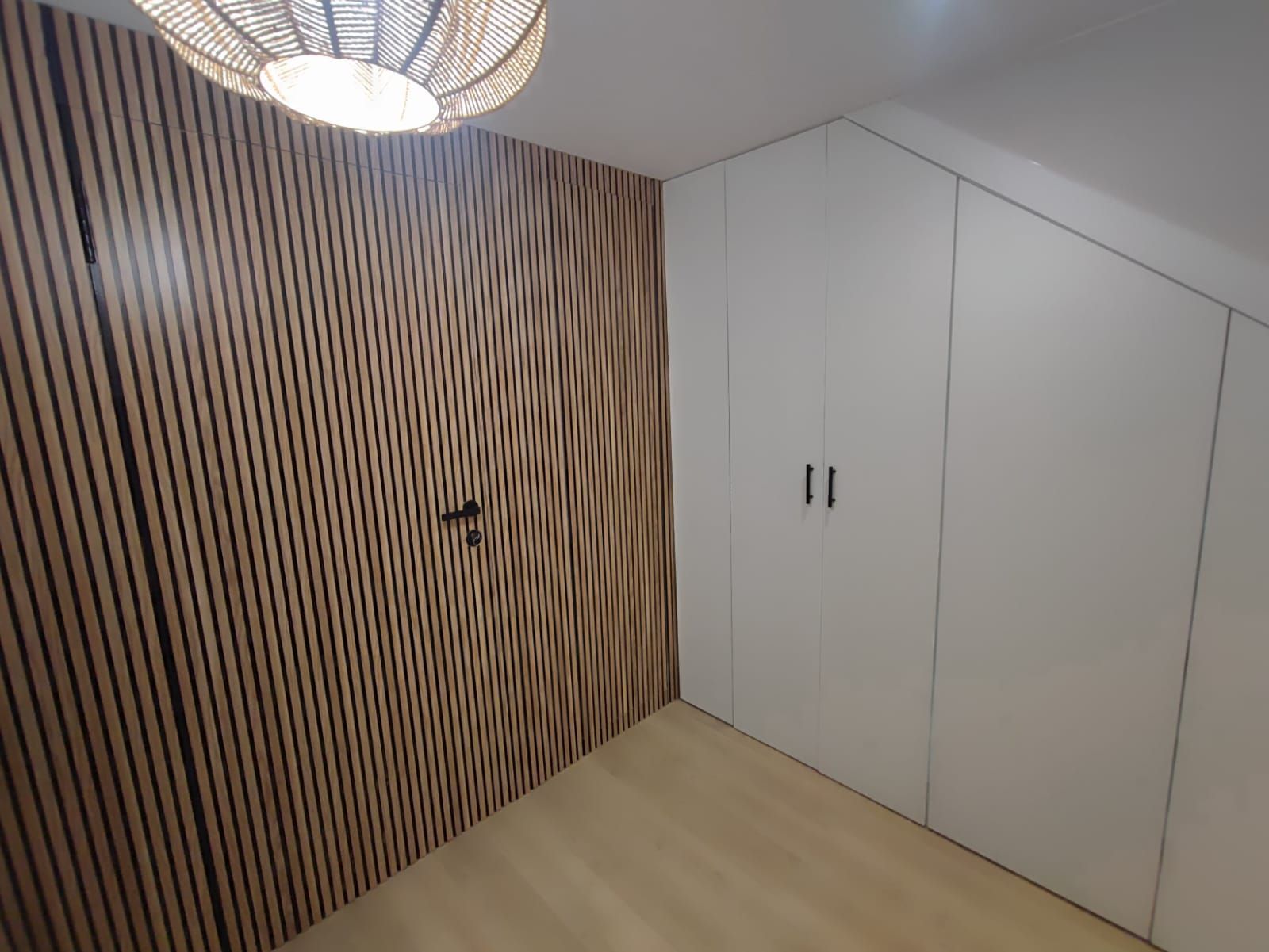 Una habitación con una pared de madera y armarios blancos.