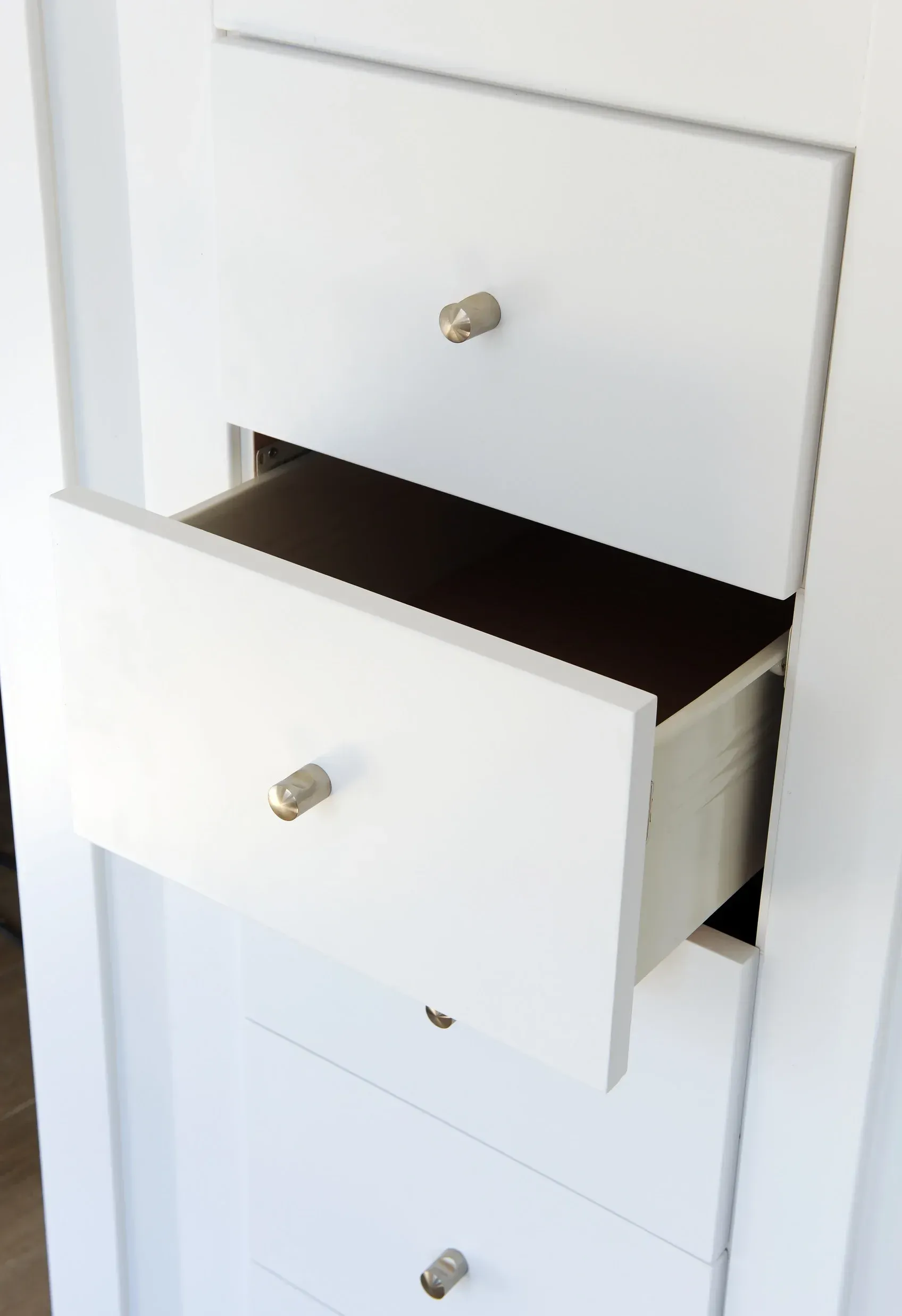 Una cómoda blanca con un cajón abierto y un cajón cerrado.
