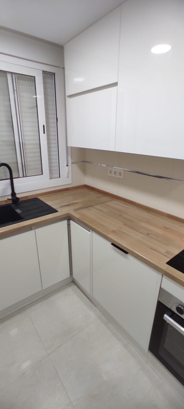 Una cocina con gabinetes blancos y encimeras de madera.