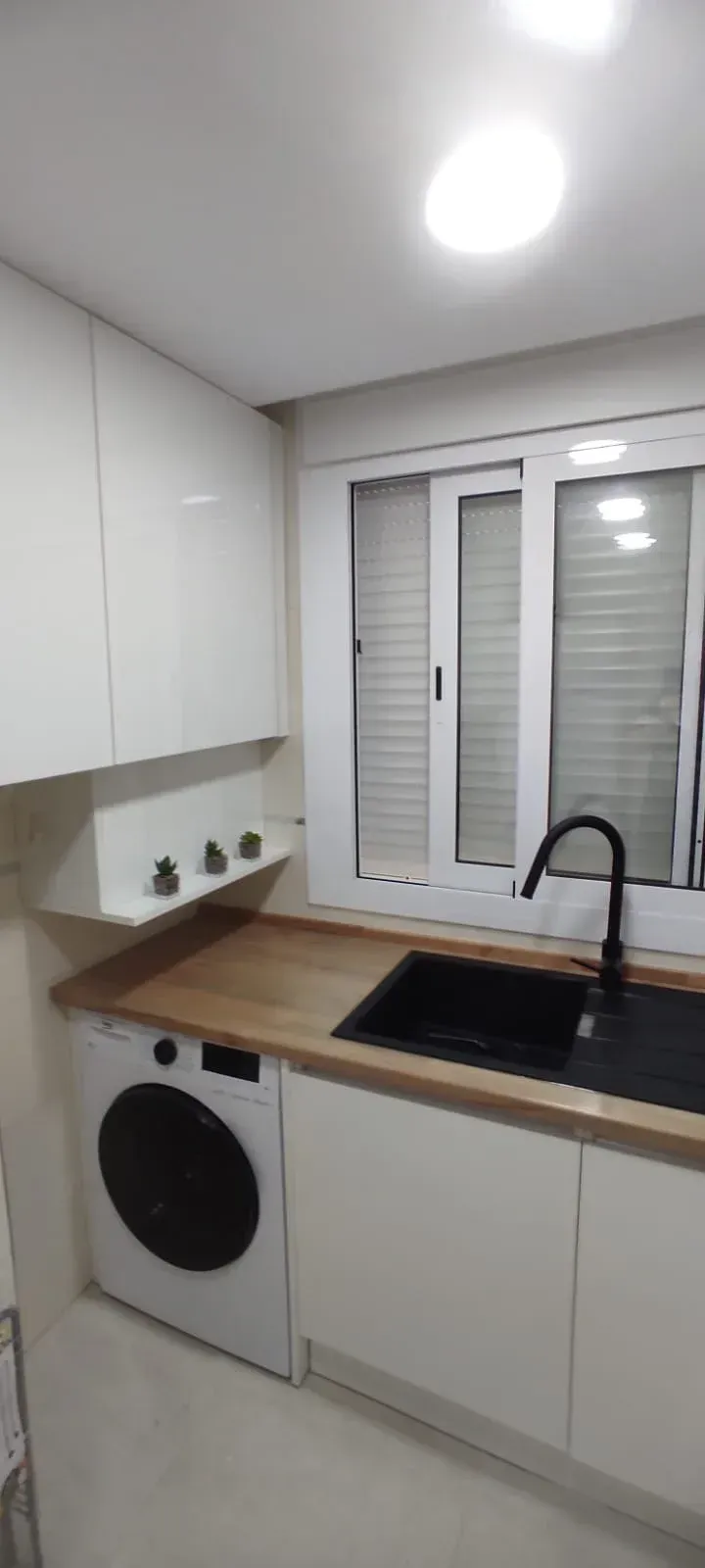 Una cocina con lavadora, fregadero y ventana.