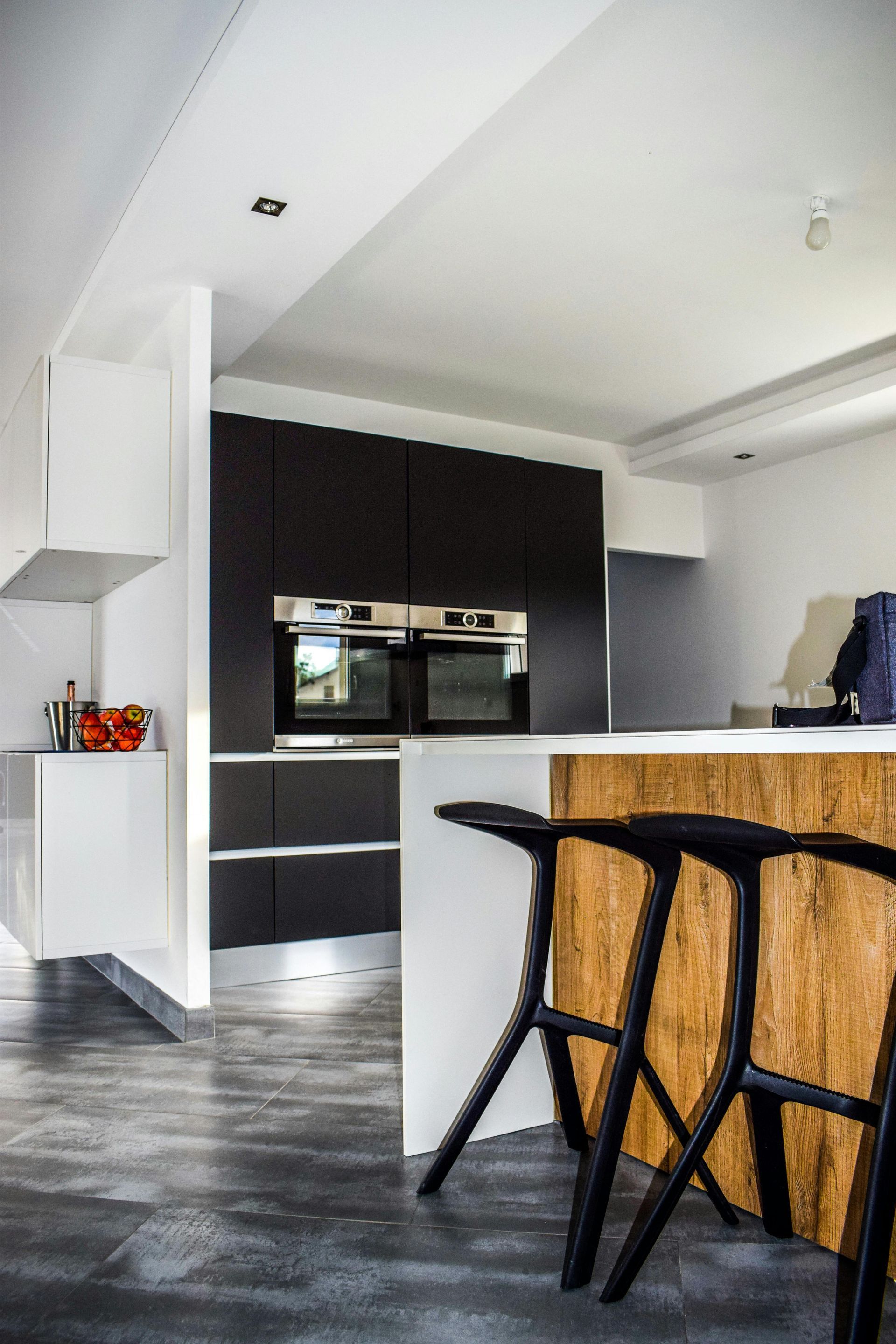 Una cocina con taburetes negros y una isla de madera.