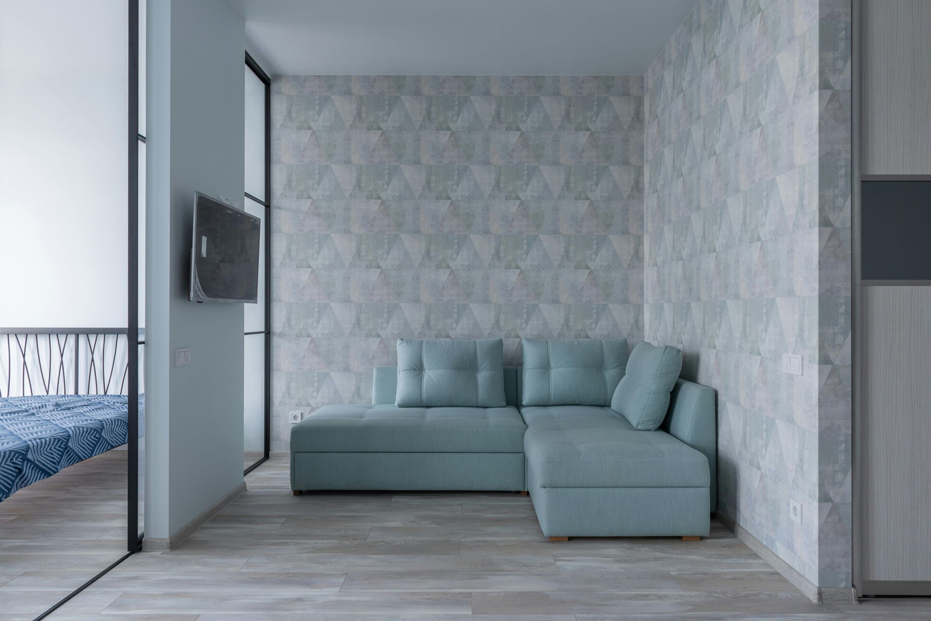 Una sala de estar con un sofá seccional azul y un televisor.
