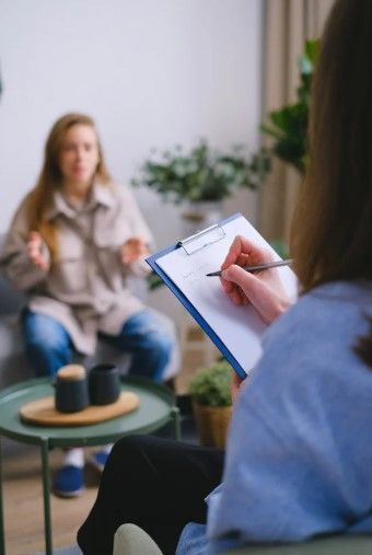 Una persona toma notas mientras otra habla en una sesión de asesoramiento.