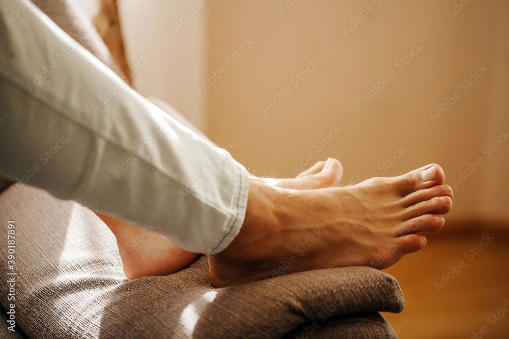 Barfuss auf einem Kissen; Bein in weisser Hose; Innenraum, natürliches Licht.