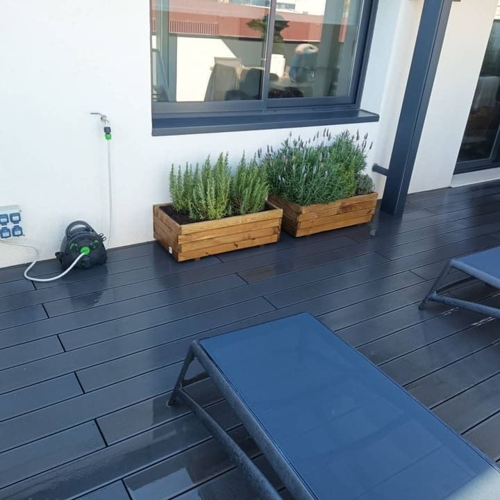 Una terraza con dos tumbonas y jardineras.