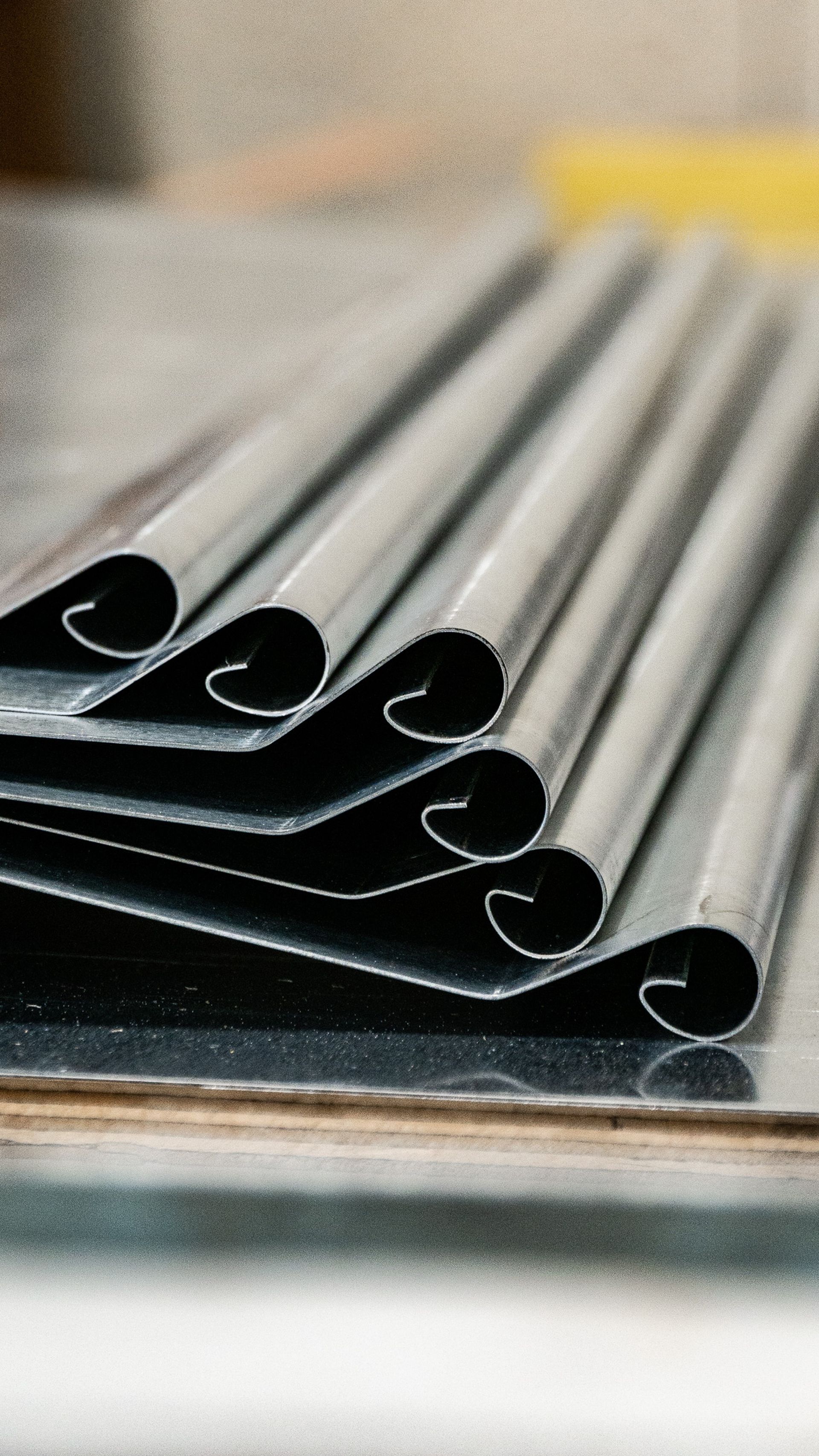 Bandes de métal laminées, empilées sur une surface de travail.