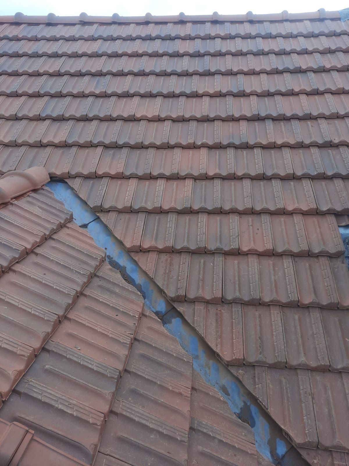 Toiture en tuiles brunes avec solins métalliques.