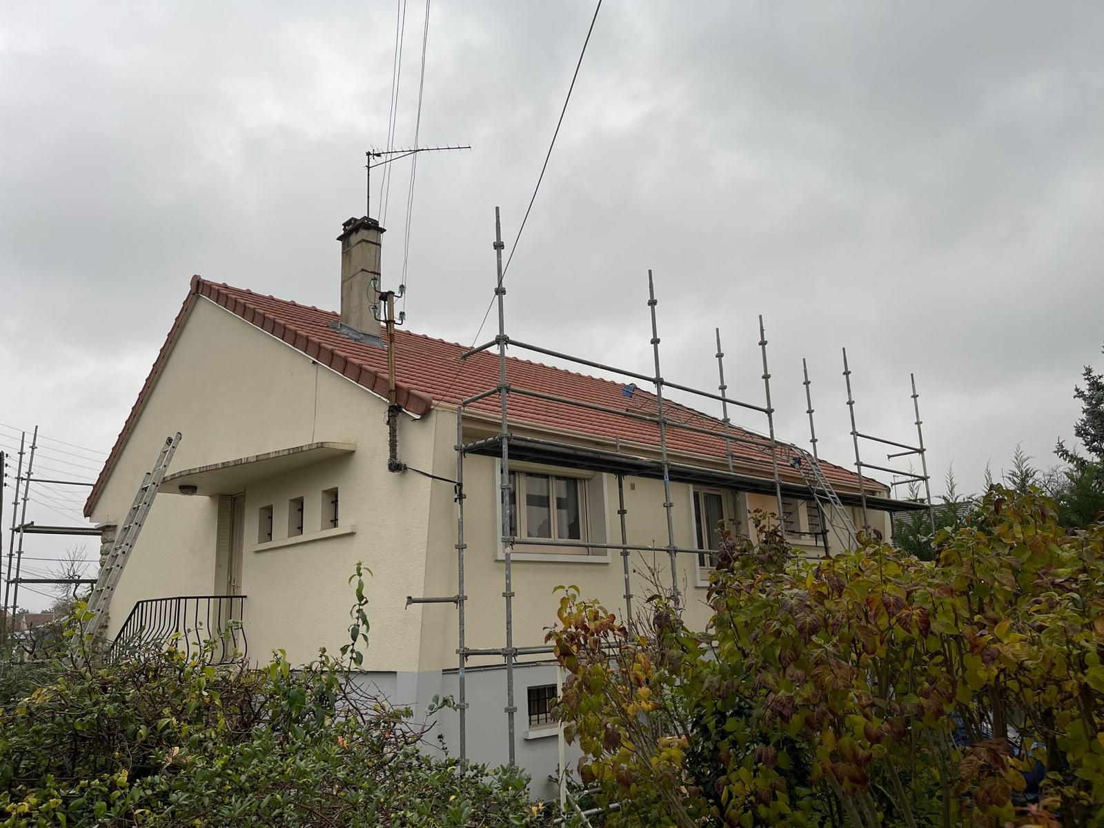 Maison avec échafaudages, toiture en travaux, ciel nuageux.