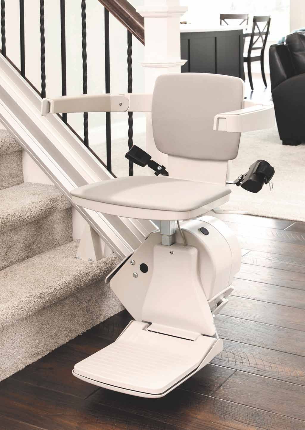 Monte-escalier sur un escalier avec siège beige et repose-pieds, à l'intérieur.