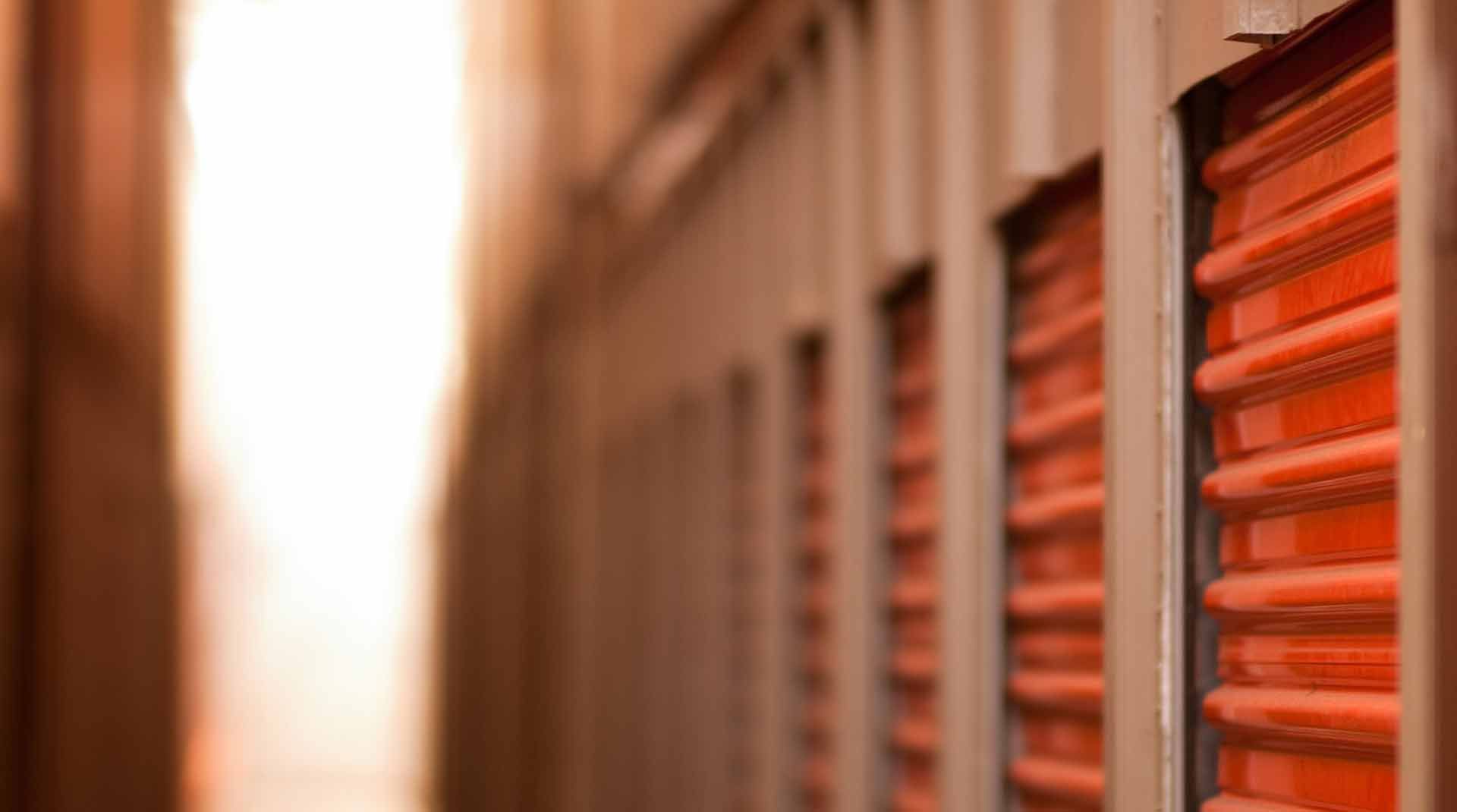 Portes orange de box de stockage dans un couloir intérieur sombre.