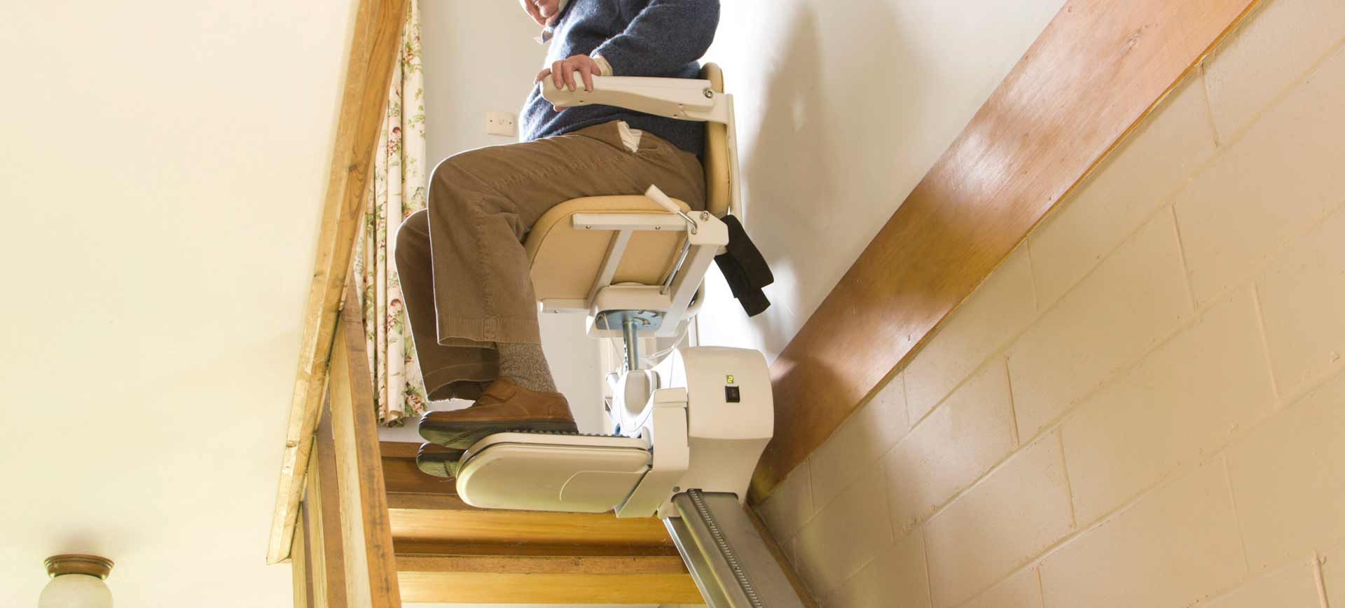 Une personne utilise un monte-escalier dans un escalier en bois à l'intérieur.