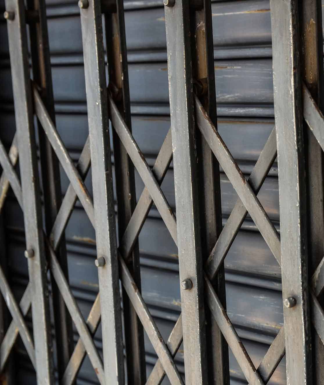 Grille de sécurité métallique à motifs entrecroisés, recouvrant une devanture de magasin.