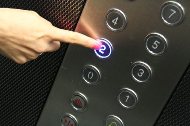 Une main appuie sur le bouton marqué « 2 » à l'intérieur d'un ascenseur.