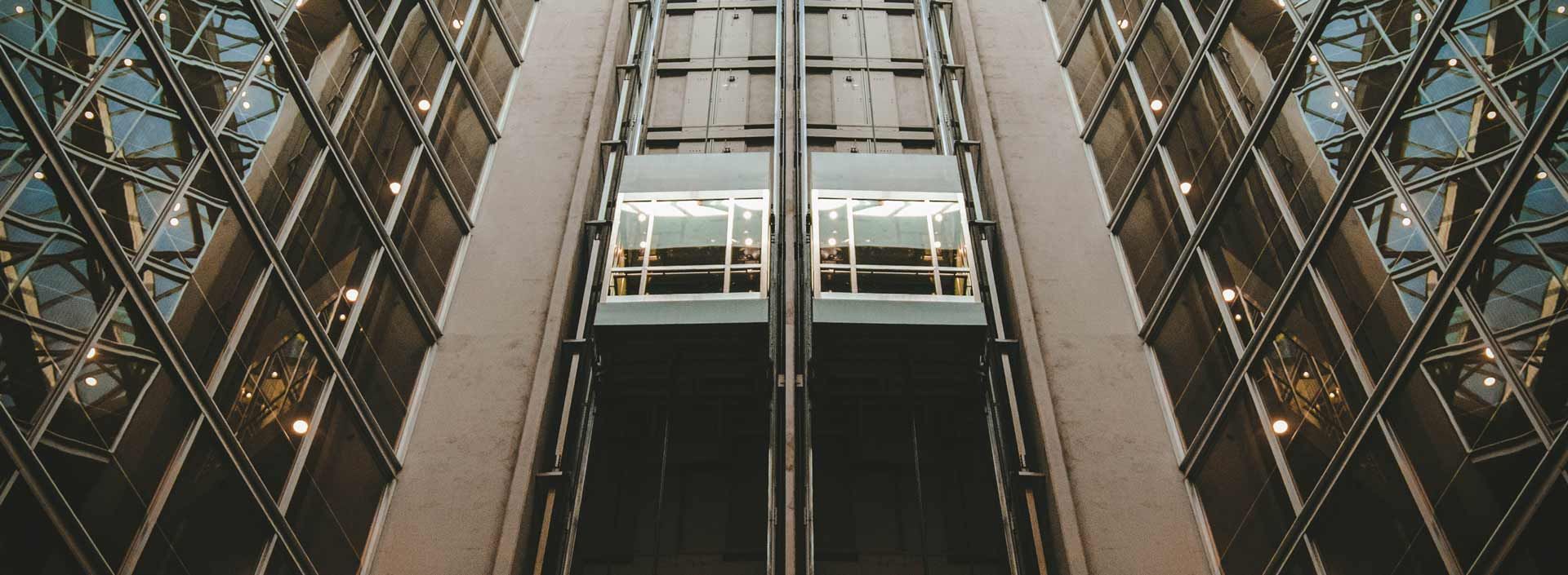 Ascenseurs dans un immeuble de grande hauteur. Façade en verre et en métal.