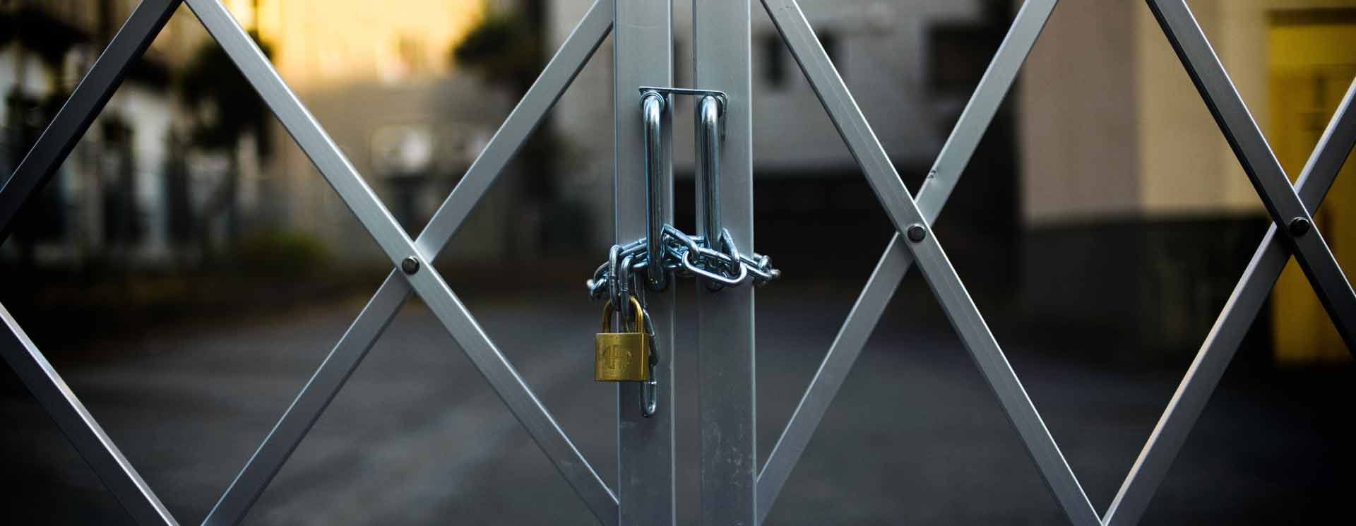 Un portail de sécurité métallique fermé à clé, muni d'une chaîne et d'un cadenas.