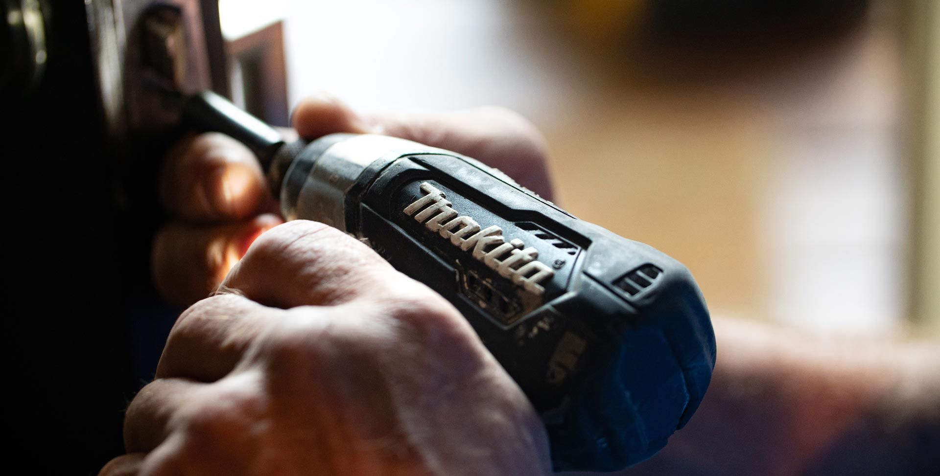 Des mains utilisent un tournevis électrique Makita pour serrer une vis.