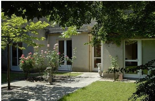 Petit jardin intérieur avec pelouse, arbres, terrasse et immeubles d'appartements en arrière-plan.