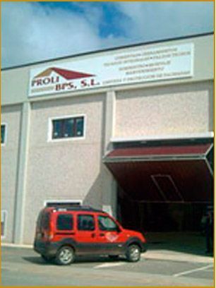 Una camioneta roja está estacionada frente a un edificio que dice proli bps sl