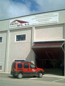 Una camioneta roja está estacionada frente a un edificio que dice proli bps sl