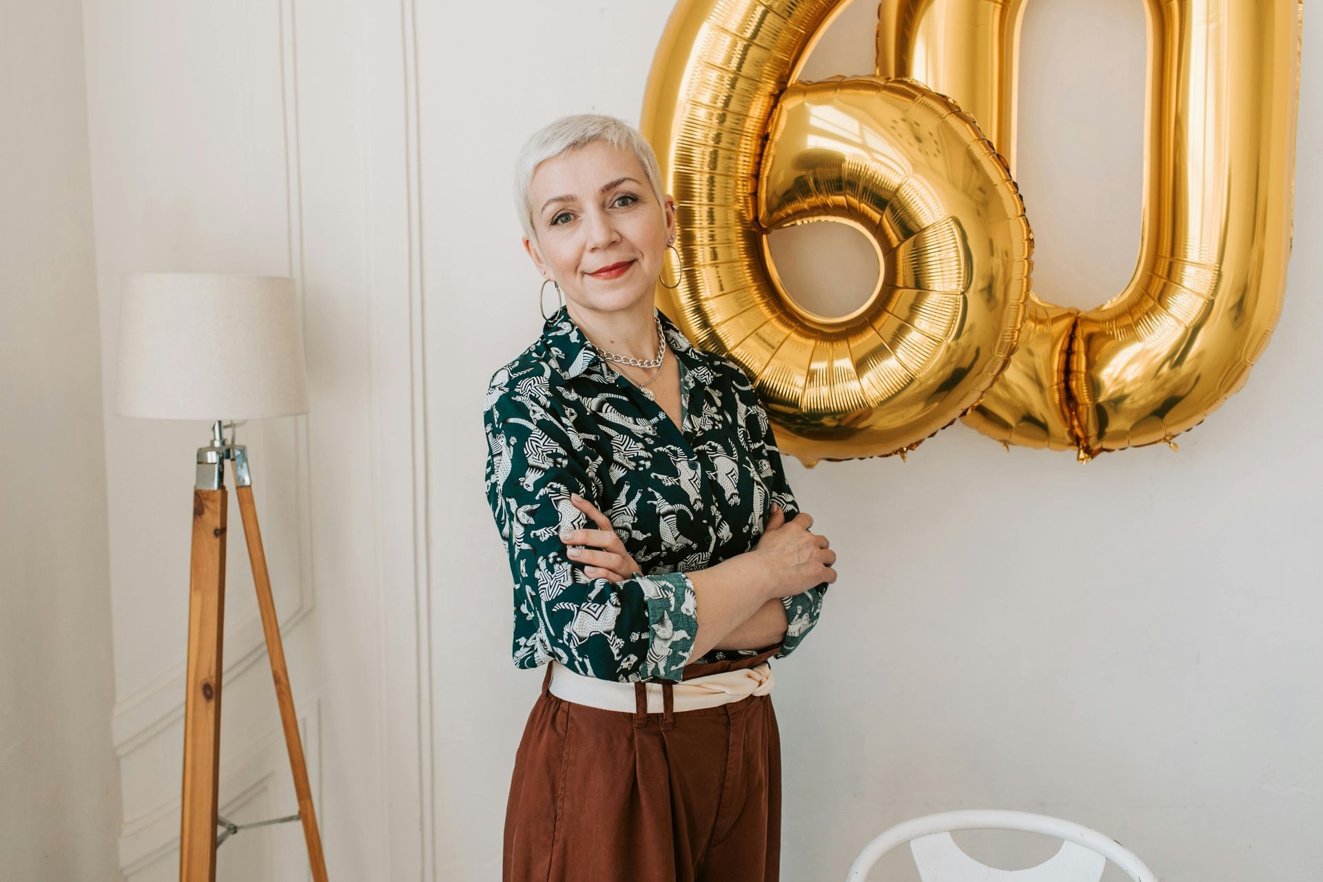 Eine Frau steht vor einer Wand mit Luftballons in Form der Zahl 60.