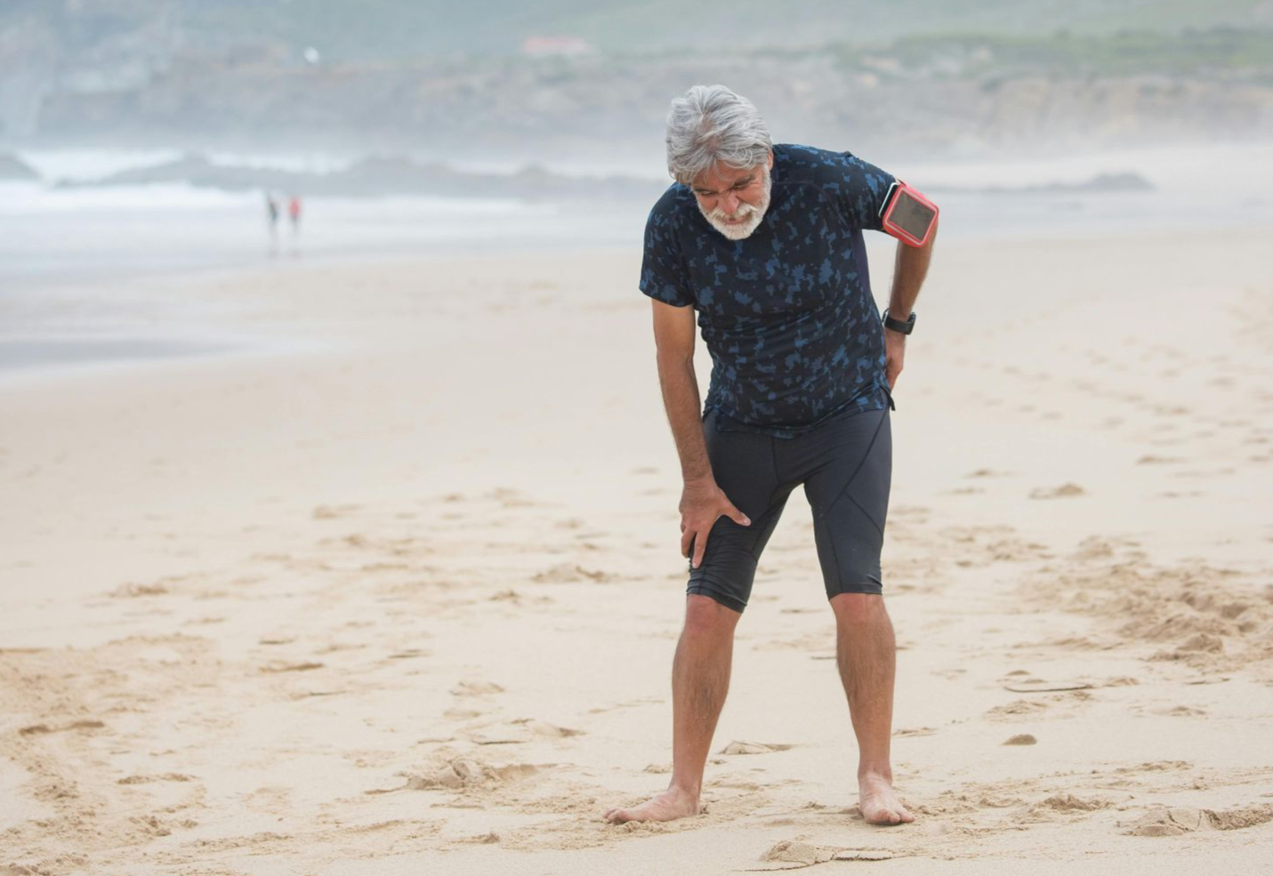 Zwei Männer trainieren mit einem Widerstandsband vor einer Backsteinmauer. Einer hilft dem anderen.