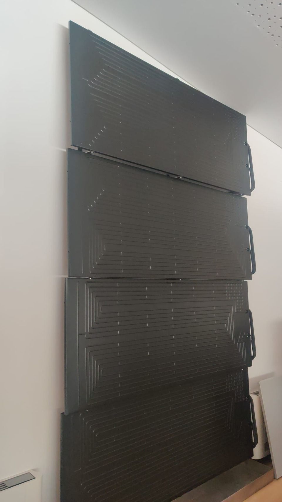 Une rangée de boîtes noires sont empilées les unes sur les autres sur un mur.