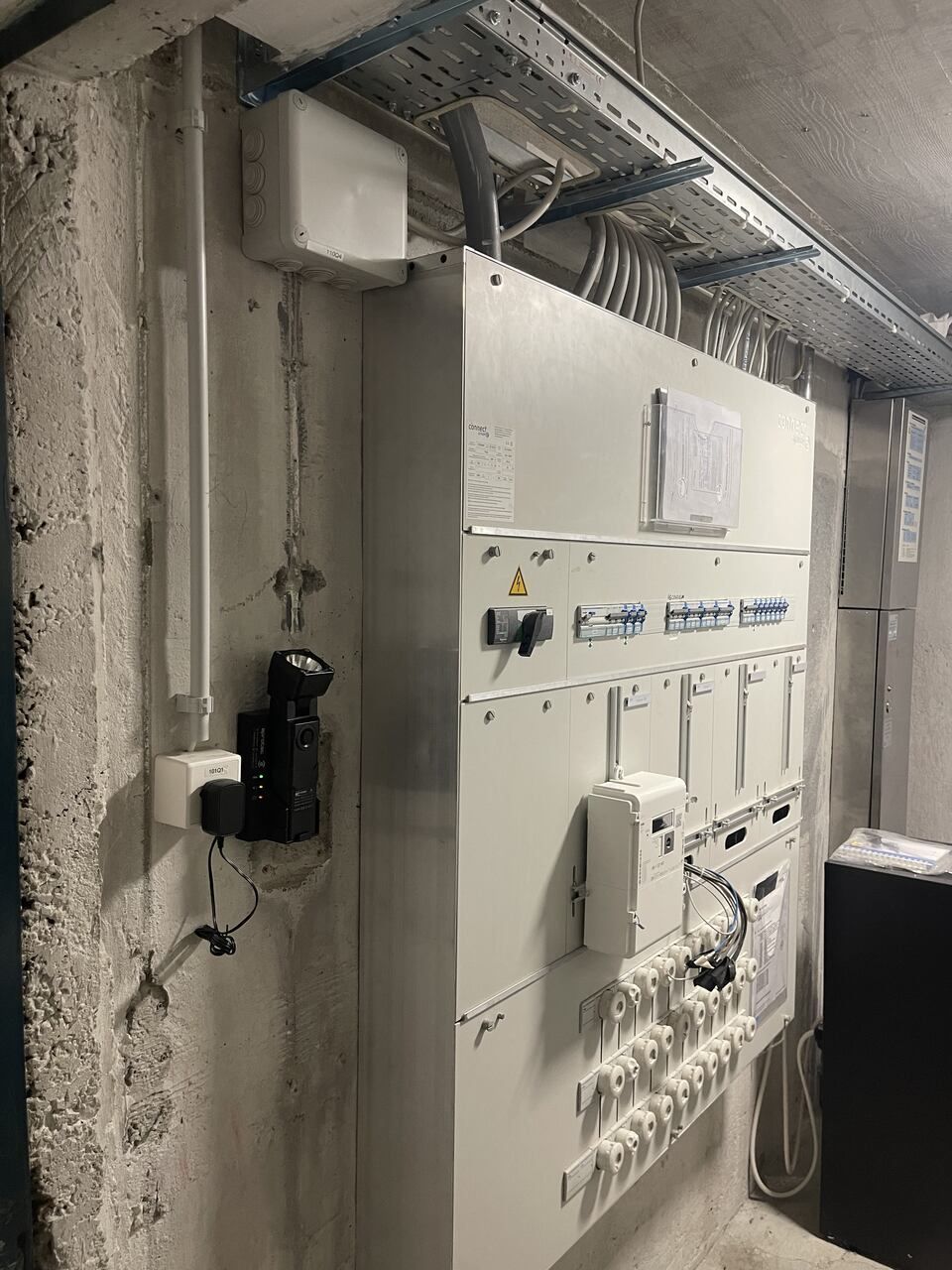 Un boîtier électrique blanc est accroché au mur d'une pièce.