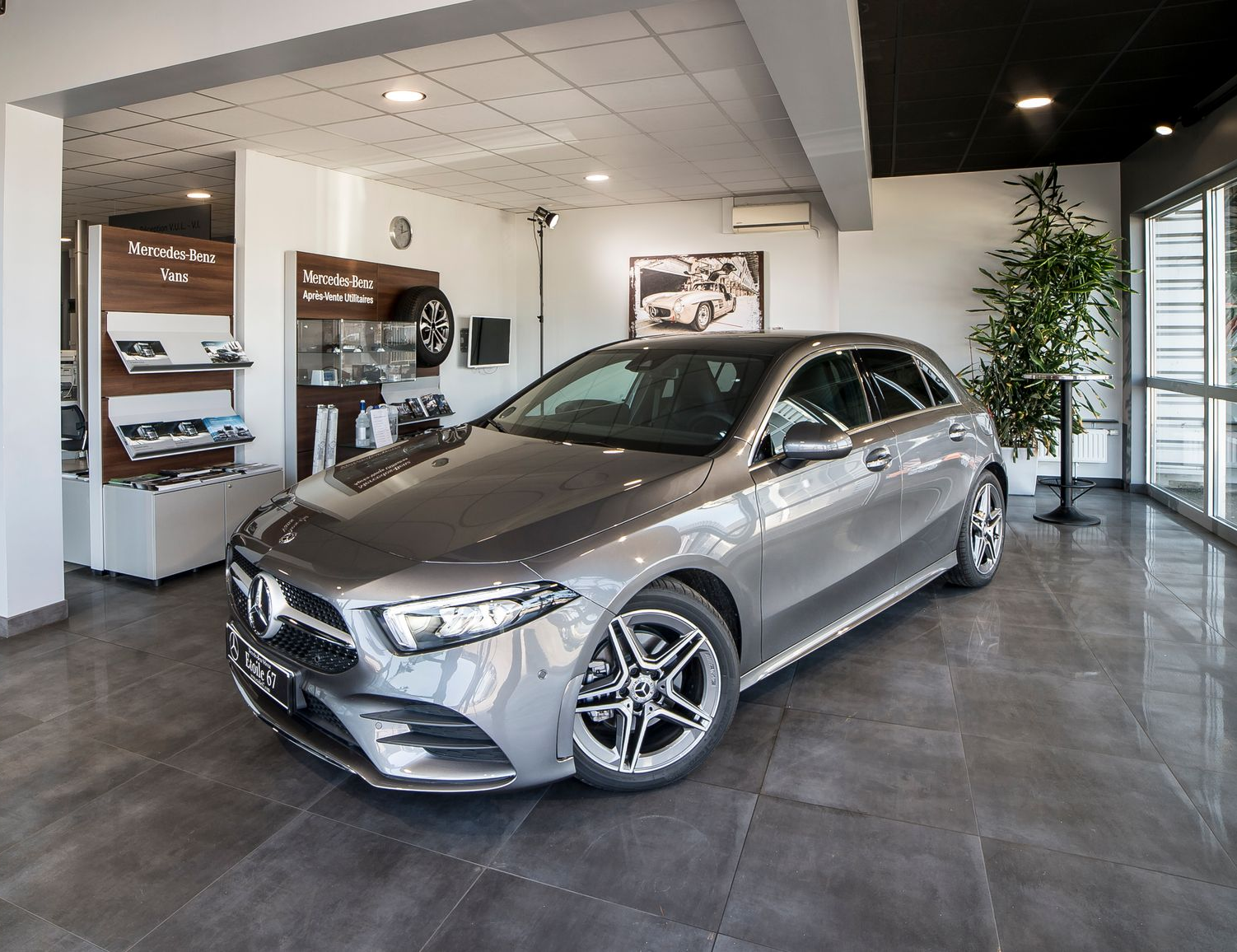 Une Mercedes-Benz Classe A à hayon argentée est garée dans un showroom automobile.