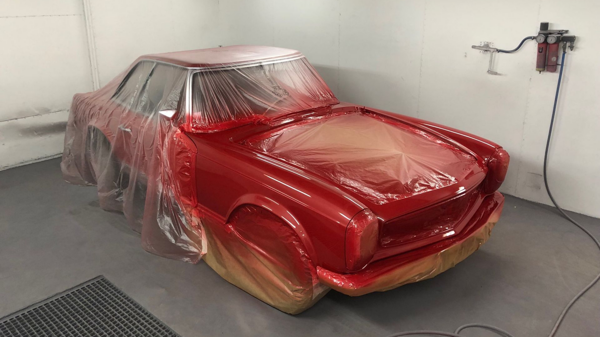Mise en peinture d'une ancienne Mercedes de couleur rouge dans une cabine.