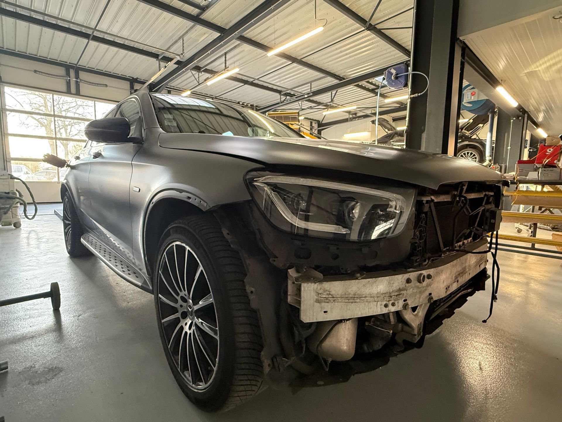 Technicien utilisant un outil de débosselage sur l'aile d'un véhicule.