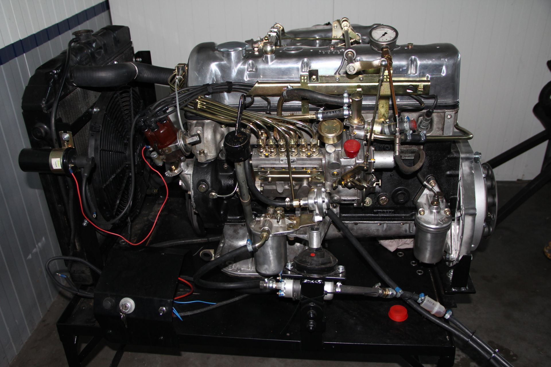 Moteur noir monté sur un support noir, avec des pièces argentées et dorées. Ventilateur de refroidissement et câbles visibles.