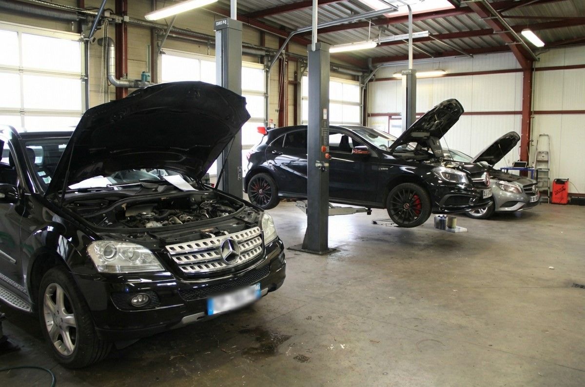 3 voitures Mercedes ont le capot levé dans un garage.