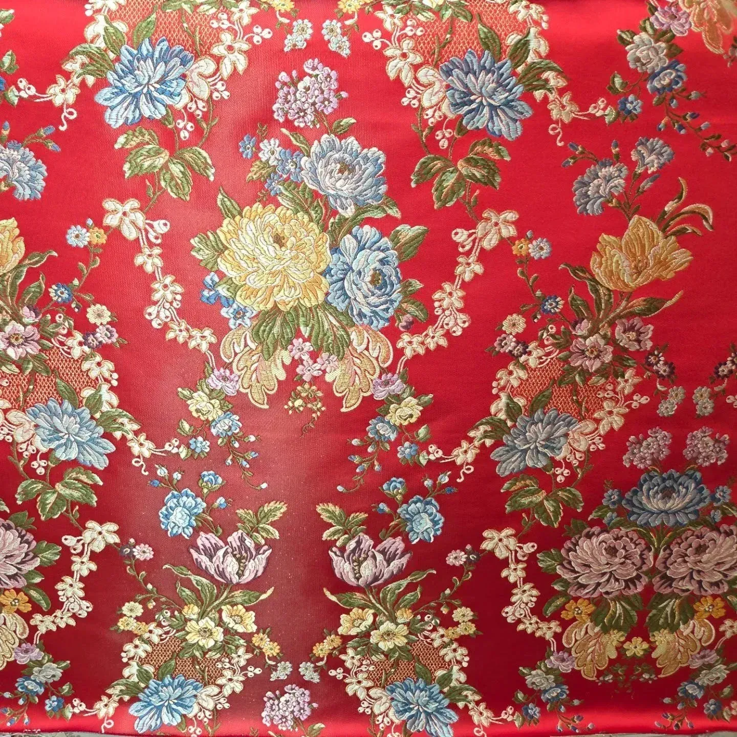 Tela roja con estampado floral en azul, amarillo y blanco.