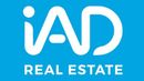 Logotipo blanco de “IAD” sobre fondo azul con el texto “REAL ESTATE” debajo.