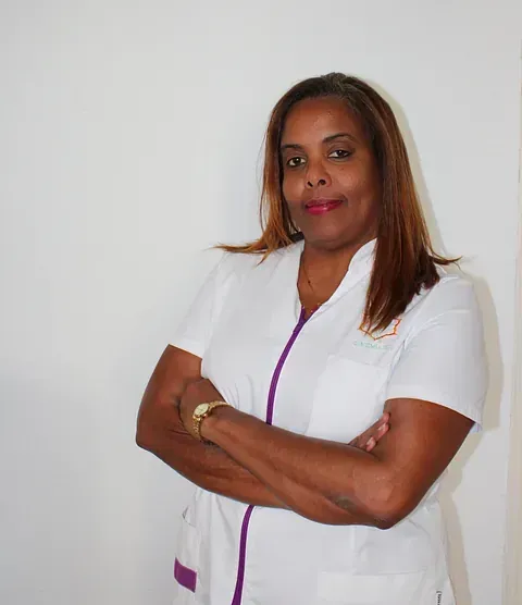 Una mujer con un uniforme blanco y morado con los brazos cruzados.