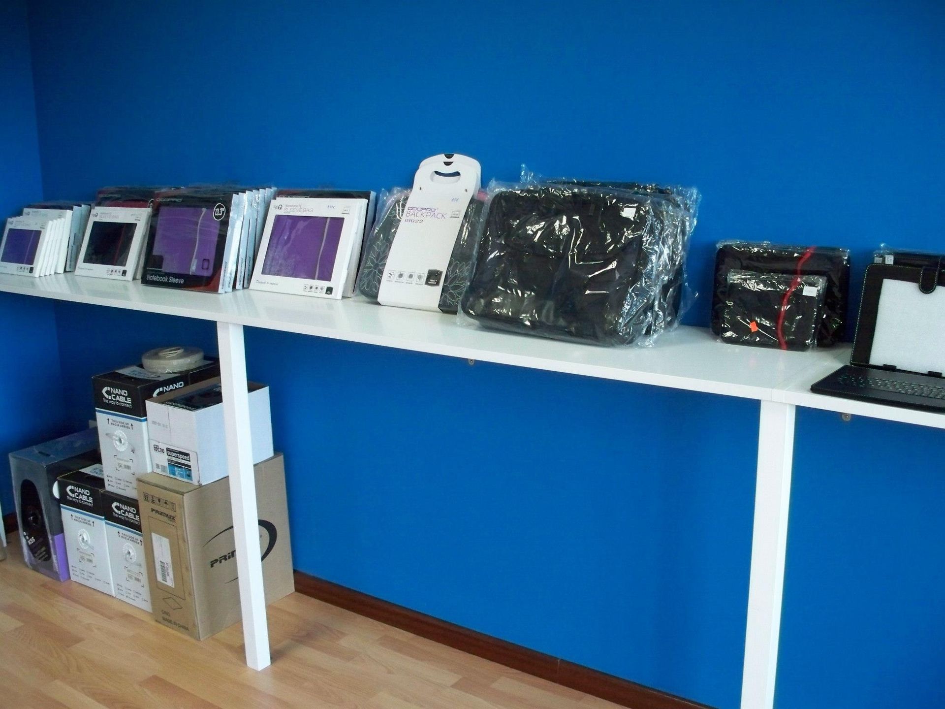 Una exhibición de computadoras portátiles y tabletas contra una pared azul.