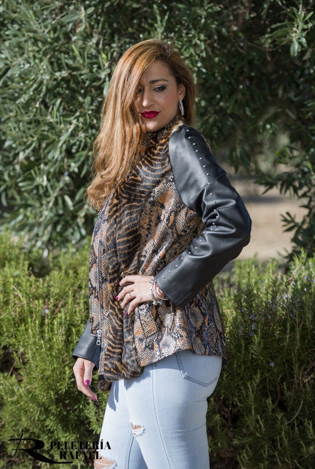 Mujer con chaqueta y jeans rotos posa al aire libre.