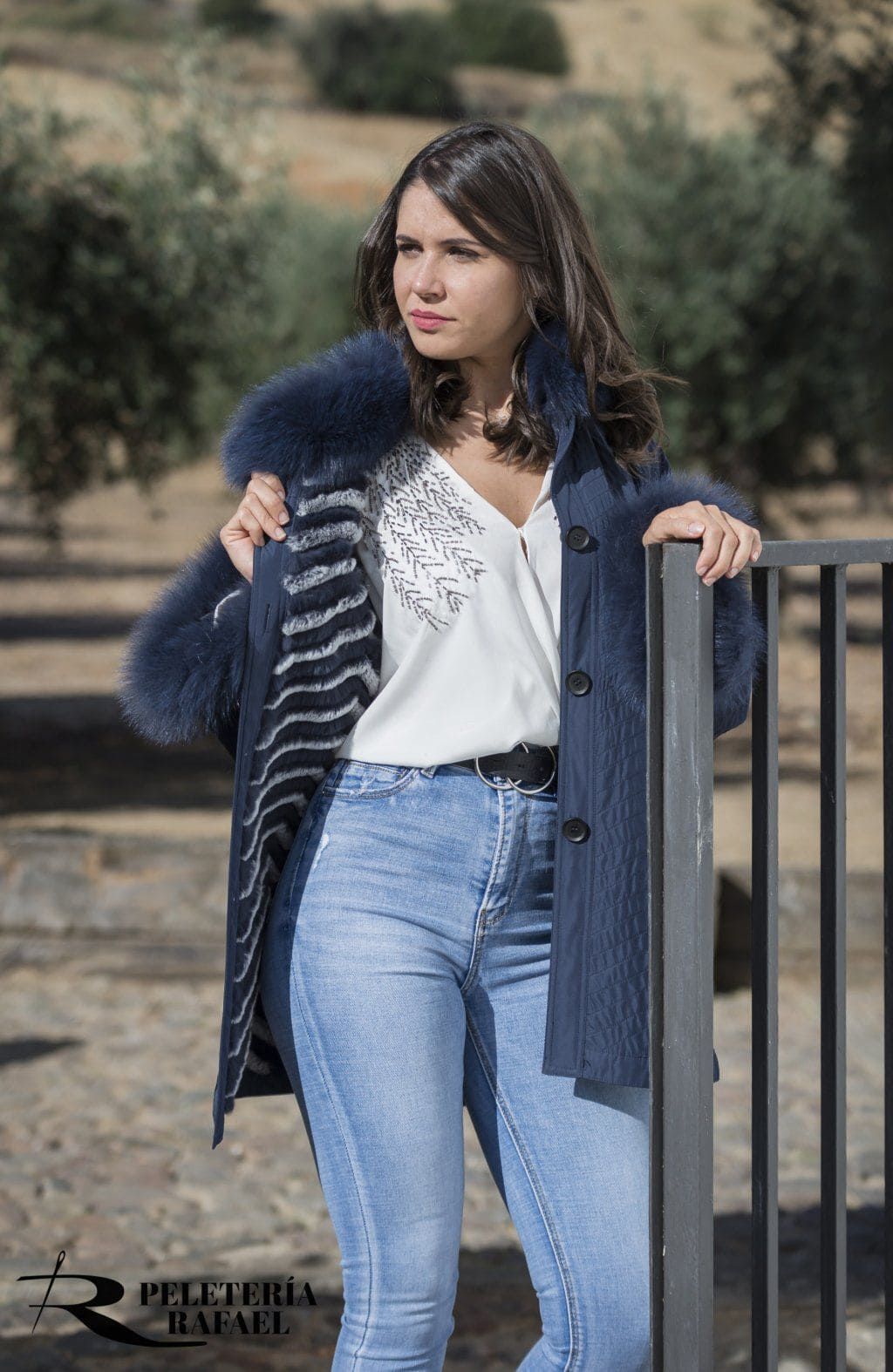 Mujer con chaqueta vaquera con ribete de piel, top blanco y jeans, al aire libre.