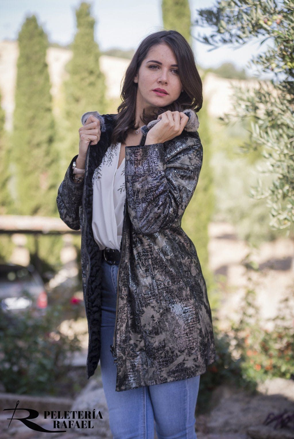 Mujer con abrigo de lentejuelas y jeans afuera, sosteniendo el cuello, mirando hacia un lado.