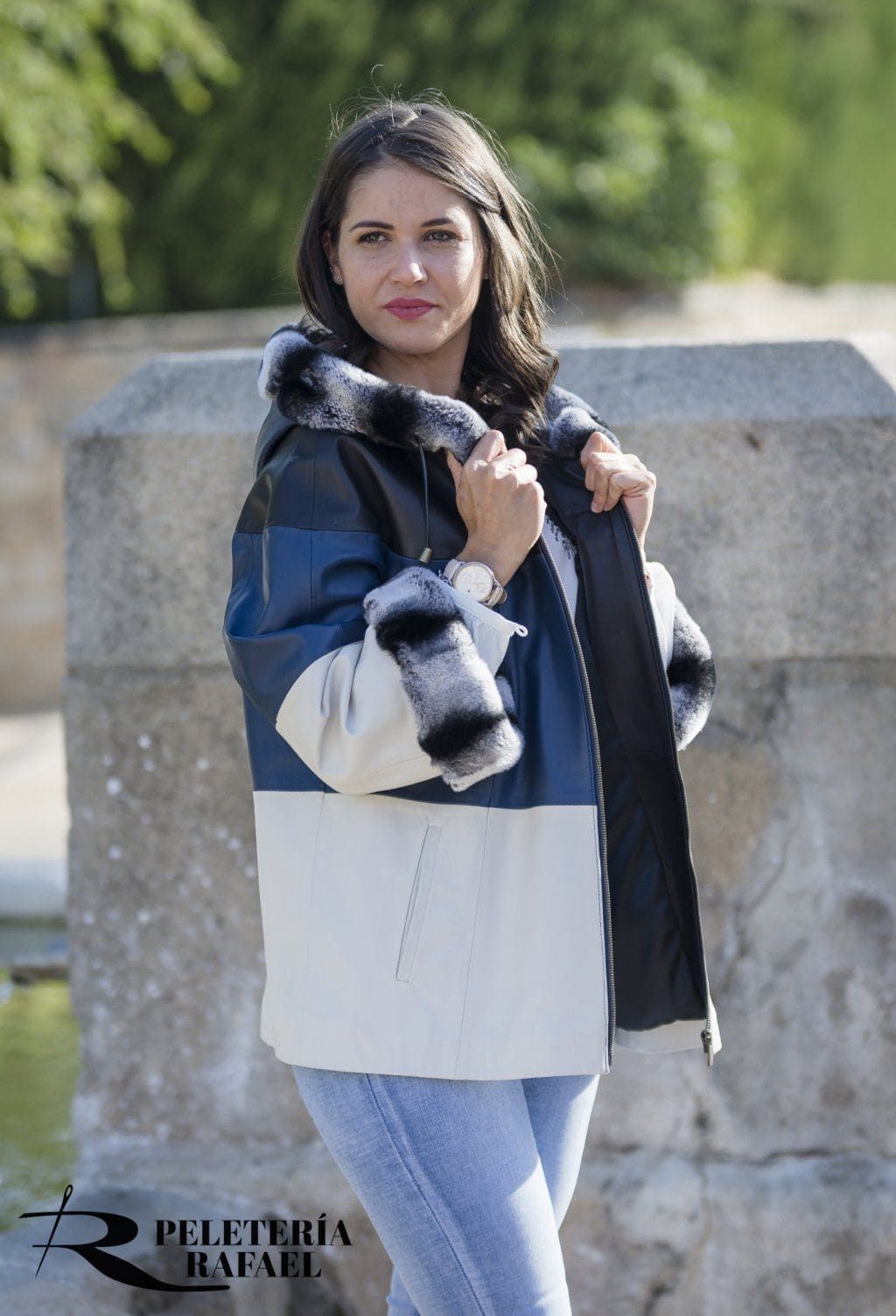 Mujer que lleva una chaqueta de cuero con bloques de color y ribete de piel, de pie al aire libre.