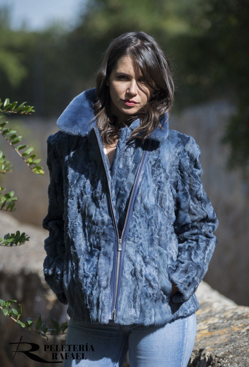 Mujer que lleva una chaqueta de piel azul con cremallera en la parte delantera, de pie al aire libre.
